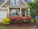 Inviting front porch with decorative landscaping and colorful flowers adds curb appeal to the home at 1008 Whipcord Dr, Waxhaw, NC 28173