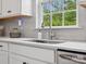 Kitchen sink featuring stainless steel faucet, white cabinets, gray subway tile backsplash and bright light at 1008 Whipcord Dr, Waxhaw, NC 28173