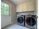 Laundry room featuring cabinets, tile flooring, a door to the exterior, and modern washer/dryer units at 1335 33Rd Avenue Ne Dr, Hickory, NC 28601