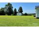 Large backyard featuring a storage shed, lush green lawn, and mature trees on a sunny day at 147 Dutchman Rd, Harmony, NC 28634