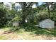 Backyard featuring mature trees, green grass, and two storage sheds in a wooded setting at 1541 Kings Rd, Shelby, NC 28150