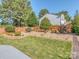 Landscaped backyard with mature trees, lush green lawn, and a charming wooden fence at 15739 Circlegreen Dr, Charlotte, NC 28273