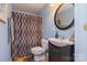 Comfortable bathroom features a vanity with oval mirror, shower with patterned curtain, and toilet at 260 River Country Rd, Salisbury, NC 28146