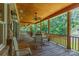Covered porch with wooden ceiling, stone supports, dining table and seating overlooking wooded backyard at 260 River Country Rd, Salisbury, NC 28146