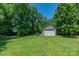 Picture of detached garage building behind the home with large grassy lawn and mature trees at 260 River Country Rd, Salisbury, NC 28146