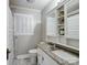 Bathroom featuring a vanity with granite countertop, white cabinets, and decorative shelving at 409 E 18Th St, Kannapolis, NC 28083