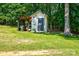 Small storage shed surrounded by lush greenery, set on a well-maintained lawn at 5390 Hudson Rd, Clover, SC 29710