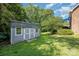 View of the shed and backyard with grassy lawn and small patio in a well-maintained landscape at 610 Mountain Pl, Albemarle, NC 28001