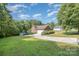 View of home's side-entry garage, paved driveway, and spacious lawn with storage shed at 610 Mountain Pl, Albemarle, NC 28001
