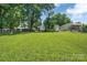 Expansive backyard with green grass, a large shade tree, and a well-maintained fence at 6208 Karenstone Dr, Charlotte, NC 28215
