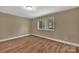 Neutral bedroom boasts new flooring and a window overlooking a tree-filled backyard at 6208 Karenstone Dr, Charlotte, NC 28215