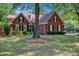 Charming brick home with manicured lawn, mature trees, and classic architectural details at 7014 Walton Heath Ln, Charlotte, NC 28277