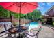 Back patio with an outdoor dining set with a red umbrella near the sparkling pool at 7014 Walton Heath Ln, Charlotte, NC 28277