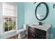 Bathroom with a round mirror, dark vanity, and a commode at 8000 Pelorus Ln, Charlotte, NC 28269