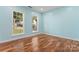 Bright, empty bedroom with hardwood floors and two large windows at 8000 Pelorus Ln, Charlotte, NC 28269
