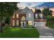 Charming brick and siding home featuring a well-manicured lawn and two-car garage at dusk at 8000 Pelorus Ln, Charlotte, NC 28269