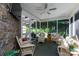 Cozy sunroom with stone walls, comfortable wicker seating, a ceiling fan, and screened windows overlooking green landscape at 804 Creek Bluff Rd, Rock Hill, SC 29732
