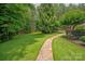 A walkway made of pavers winds through a professionally manicured backyard surrounded by mature trees at 9110 Woodhall Lake Dr, Waxhaw, NC 28173