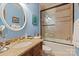 Bright bathroom with a shower-tub combo, warm brown wooden vanity, granite countertop and blue walls at 9110 Woodhall Lake Dr, Waxhaw, NC 28173