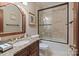Bathroom with granite vanity, framed mirror, and tile-surround bathtub with glass door at 9110 Woodhall Lake Dr, Waxhaw, NC 28173