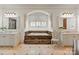 Elegant bathroom featuring a marble-encased tub, dual vanities, and arched window niche at 9110 Woodhall Lake Dr, Waxhaw, NC 28173