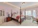 Spacious bedroom with a four-poster bed, sitting area, and light pink walls, creating a serene and elegant atmosphere at 9110 Woodhall Lake Dr, Waxhaw, NC 28173