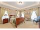 Comfortable bedroom featuring a wood bed frame, large windows with decorative curtains, and a cozy sitting area at 9110 Woodhall Lake Dr, Waxhaw, NC 28173