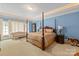 Inviting bedroom with four poster bed, sitting area, and bright blue walls, offering a blend of elegance and comfort at 9110 Woodhall Lake Dr, Waxhaw, NC 28173