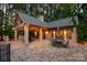 Back exterior view of a covered brick patio with outdoor seating, lush trees, and inviting lighting for evening enjoyment at 9110 Woodhall Lake Dr, Waxhaw, NC 28173
