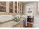 Well-appointed pantry with glass-front cabinets, granite countertops, and a wine refrigerator at 9110 Woodhall Lake Dr, Waxhaw, NC 28173