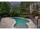 A serene in-ground pool with stone trim and brick pavers is surrounded by lush landscaping and a privacy fence at 9110 Woodhall Lake Dr, Waxhaw, NC 28173
