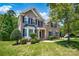 Traditional two-story brick home with mature trees, lush lawn, and welcoming front porch at 10104 Treetop Ln, Cornelius, NC 28031