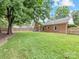 Spacious backyard with a well-maintained lawn, brick house, chimney and wood fence at 1115 Berry Ridge Rd, Charlotte, NC 28270