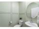 Powder room features decorative paneled walls, toilet, modern sink, and round mirror at 135 Orson Oaks Ln, Pineville, NC 28134