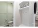 Powder room features decorative paneled walls, toilet, white shelving, hooks, and modern accents at 135 Orson Oaks Ln, Pineville, NC 28134