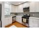 Bright kitchen with stainless steel appliances, stylish tile backsplash, white cabinets and hardwood floors at 215 Cedar St, Belmont, NC 28012