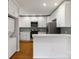 Bright kitchen features stainless steel appliances, white cabinets, mosaic tile backsplash and hardwood floors at 215 Cedar St, Belmont, NC 28012