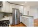 Bright kitchen features stainless steel appliances, white cabinets, mosaic tile backsplash and hardwood floors at 215 Cedar St, Belmont, NC 28012
