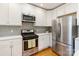 Bright kitchen features stainless steel appliances, white cabinets, mosaic tile backsplash and hardwood floors at 215 Cedar St, Belmont, NC 28012