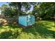 A backyard features a well-kept blue shed and lush green grass with mature trees for a peaceful environment at 215 Cedar St, Belmont, NC 28012