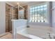 Bright bathroom featuring a glass shower, a soaking tub, and a glass block window at 2630 Filson Ct, Charlotte, NC 28214