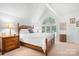 Bright and airy main bedroom showcasing vaulted ceilings, a large arched window, and elegant wooden furnishings at 2704 Apache Trl, Denver, NC 28037