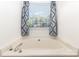Soaking tub next to a window offering natural light and privacy with decorative curtains at 2916 Northwood Dr, Monroe, NC 28110