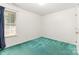 Empty bedroom with teal carpet, a window, and neutral colored walls at 2916 Northwood Dr, Monroe, NC 28110