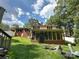 Back exterior with a screened in porch and brick and tan siding surrounded by green grass with a chair in the shot at 408 E Blume St, Landis, NC 28088