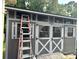 The exterior of a well-maintained backyard shed features gray siding and charming white trim with black hardware and accents at 408 E Blume St, Landis, NC 28088