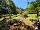 A spacious backyard with tiered landscaping, mature trees, and a glimpse of the house in the background at 44112 Harper Hearne Rd, New London, NC 28127