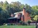 Charming log cabin with a brick chimney, dormer windows, and a covered porch nestled amongst mature trees at 485 Johnson St, China Grove, NC 28023