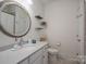 Clean bathroom featuring white vanity, a decorative round mirror, and neutral tile flooring at 5268 Courtyard Ln, Belmont, NC 28012