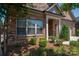 Close-up of a brick house featuring manicured landscaping, including shrubs and small trees at 5268 Courtyard Ln, Belmont, NC 28012